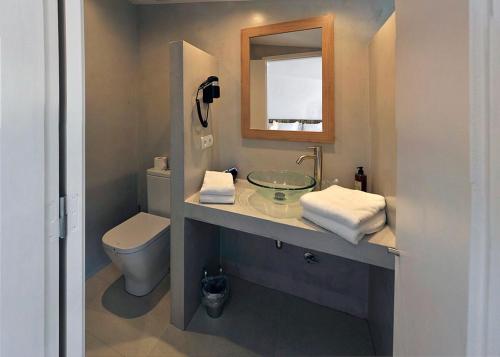 a bathroom with a sink and a toilet and a mirror at Arrels Hotel Cadaques - Adults Only in Cadaqués