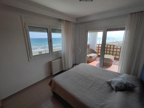 a bedroom with a bed and a view of the ocean at First line houses in Sozopoli
