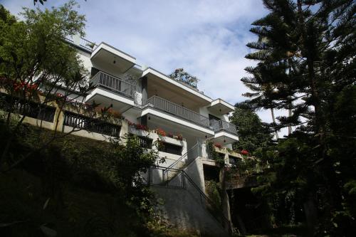 a white building with flowers on a balcony at Sceva's Garden Home in Munnar