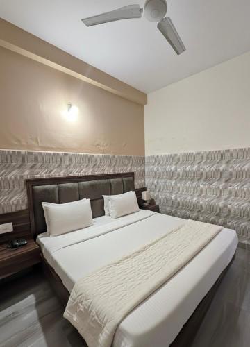 a bedroom with a large bed with white sheets at Mahajan Lodge in Katra