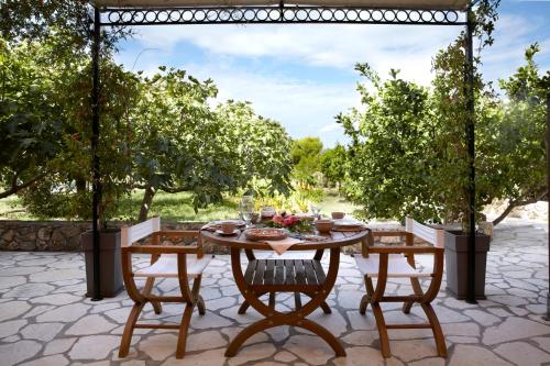 a table and chairs on a patio with trees at Avra Private Suites in Lassi