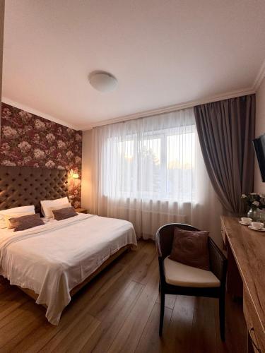 a bedroom with a bed and a chair and a window at Рандеву in Slavske