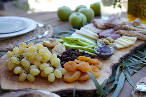 a wooden cutting board with fruits and vegetables on a table at Avra Private Suites in Lassi