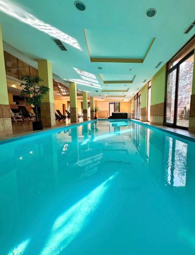 a large swimming pool with blue water in a building at Dorina Wellness Apartman in Siófok
