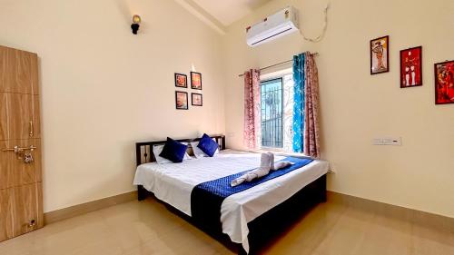 a bedroom with a bed with blue pillows and a window at Swapno Chhobi in Bolpur