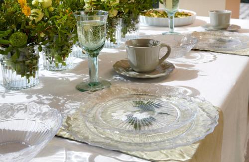 a white table with glass plates and a cup and a wine glass at Avra Private Suites in Lassi