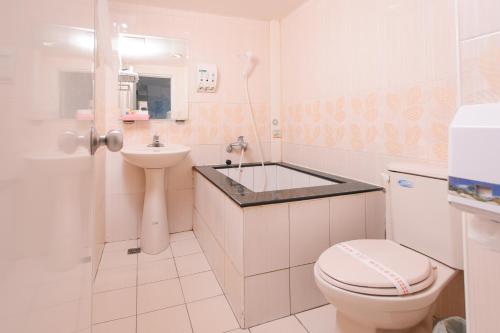 a white bathroom with a toilet and a sink at Beethoven Express Hotel in Zhongli