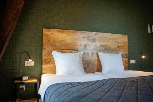 a bedroom with a large bed with a wooden headboard at Havezathe Carpe Diem in Vethuizen