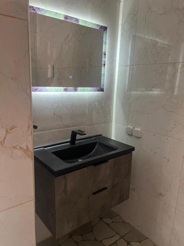 a bathroom with a black sink and a mirror at Villa Sara DIALLO in Ngaparou