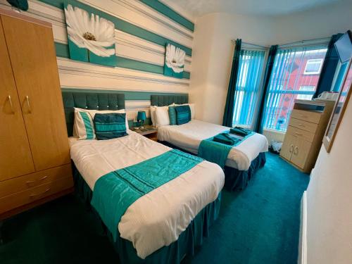 a hotel room with two beds and two windows at Beeches Hotel in Blackpool