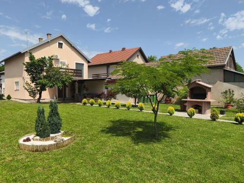 a house with a lawn with a tree in the yard at Apartmani Astra in Vukovar