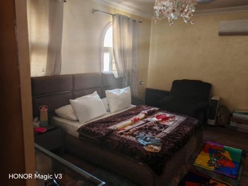 a bedroom with a bed and a chair and a window at Loay Villa Stella Helipolis in Madīnat aţ Ţalāʼi‘