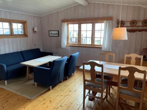 a living room with a table and blue chairs at Tyinholmen hytter in Eidsbugarden