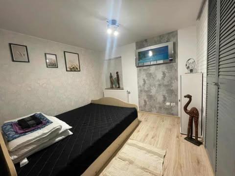 a bedroom with a black bed and a refrigerator at Domek Pluto Konradów 1 in Lądek-Zdrój