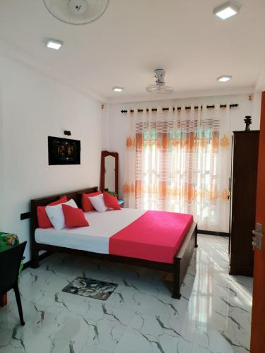 a bedroom with a large bed with red and pink sheets at OCEAN Wild Trail in Hikkaduwa