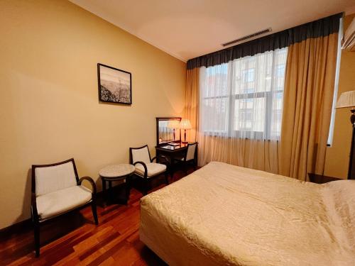 a hotel room with a bed and chairs and a window at Taj Palace Hotel & Spa in Dushanbe
