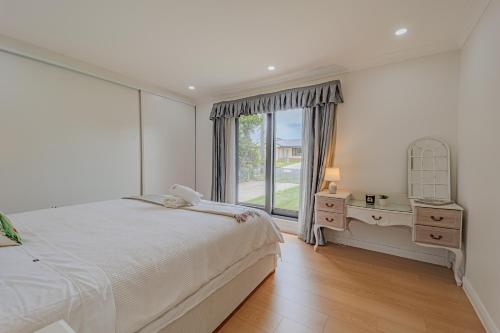 a white bedroom with a bed and a window at Villa Oberon in Oberon