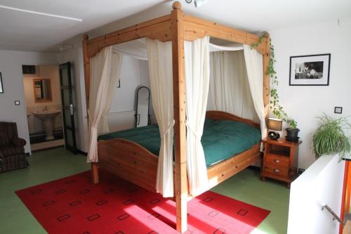 a bedroom with a wooden canopy bed with curtains at Les chambres noires in Mélisey