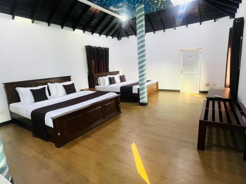 two beds in a large room with wooden floors at Palmyra resort in Jaffna