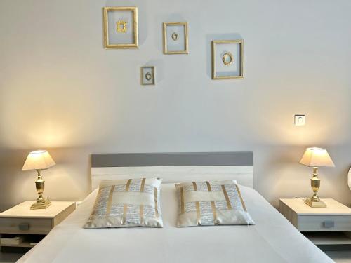 a bedroom with a white bed with two tables and two lamps at Residence D Été in Propriano