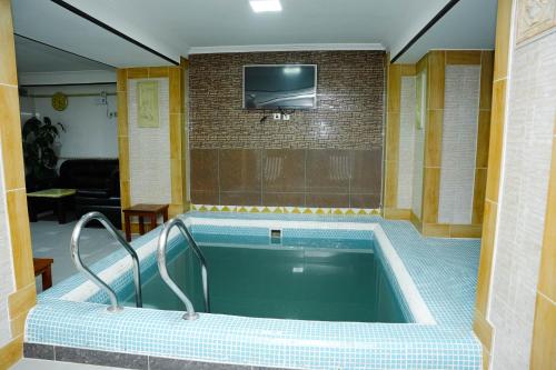a bath tub in a room with a tv at Taj Palace Hotel & Spa in Dushanbe