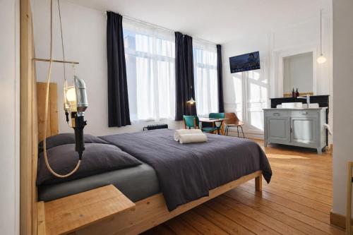 a bedroom with a large bed in a room with windows at LA MAISON FIVES - Esprit Hôtel Design - Lille in Lille