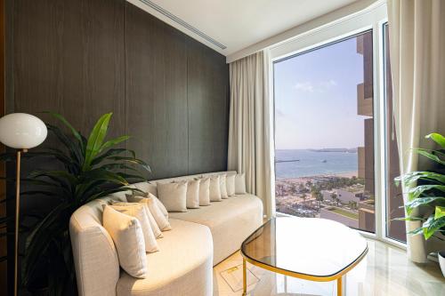 a living room with a couch and a large window at FIVE Palm Luxury 1BR Apartment with Stunning Views in Dubai