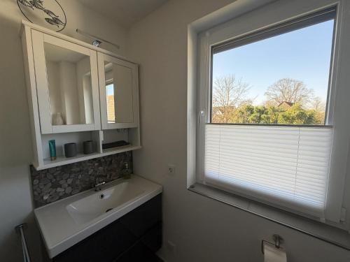 a bathroom with a sink and a window and a tub at Moderne Ferienwohnung über 2 Etagen in Bissendorf