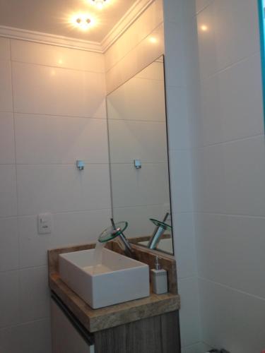 y baño con lavabo blanco y espejo. en Apartamento de Luxo em Torres, en Torres