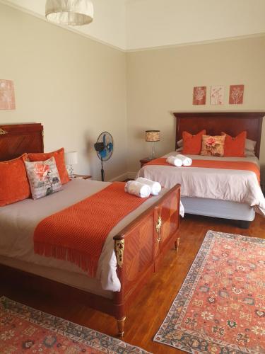 a bedroom with two beds and a rug at Philippolis - Reizigers Rust in Philippolis