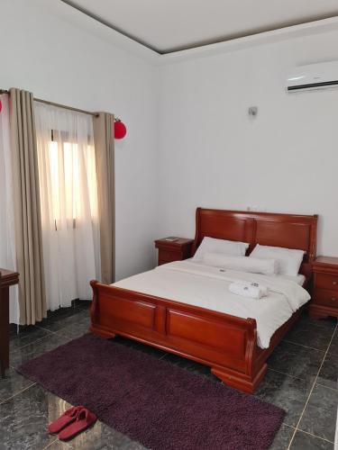 a bedroom with a wooden bed with white sheets at ADM HOTEL Grand-Lahou in Grand-Lahou