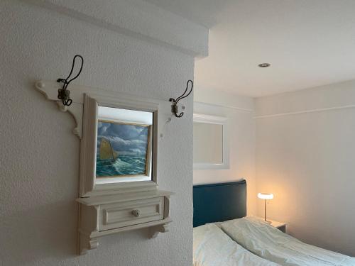 a white bedroom with a bed and a mirror at Ferienwohnung Piesch in Glücksburg