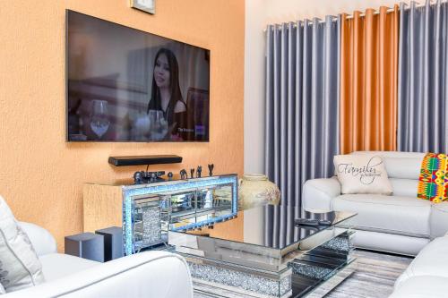 a living room with white furniture and a flat screen tv at THE AFRICAN PALACE- Free Airport Pick up - High Speed Starlink WiFi - Car Rental in Tamale