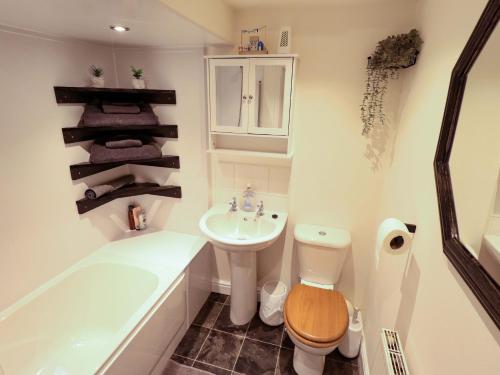 a bathroom with a tub and a toilet and a sink at 3 The Old Drill Hall in Alford