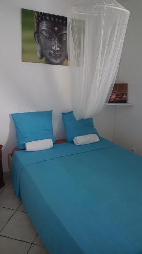 Una cama azul en una habitación con una foto en la pared en Location Marigot, en Terre-de-Haut