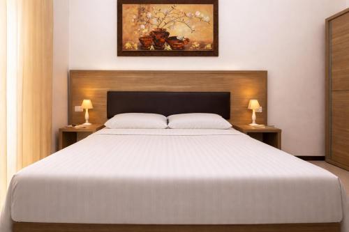 a bedroom with a large white bed with two lamps at Le Residenze del Centro in Olbia