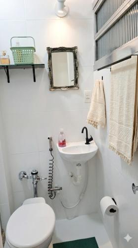 a white bathroom with a toilet and a sink at Studio Catete Flamengo in Rio de Janeiro