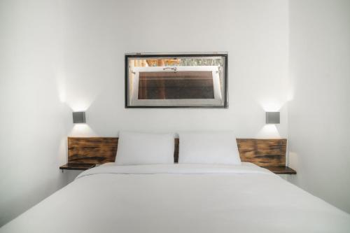 a bedroom with a white bed and a picture on the wall at Comuna Tigabelas in Gisi
