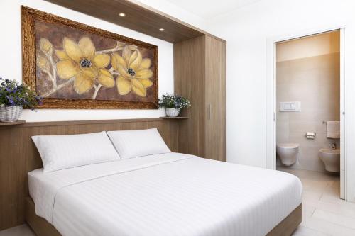 a bedroom with a white bed and a painting on the wall at Le Residenze del Centro in Olbia