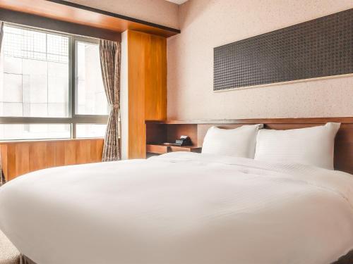 a large white bed in a room with a window at CHECK inn Express Taichung Fengchia in Taichung