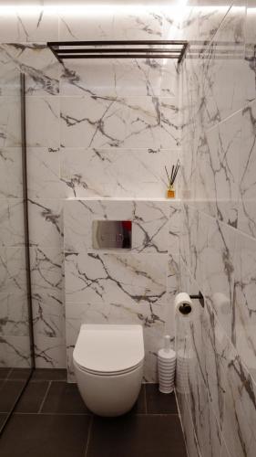 a bathroom with a white toilet and marble walls at Rancho in Ladyzhyn