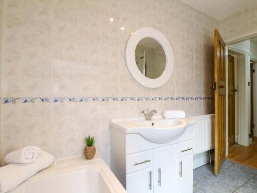 a bathroom with a sink and a tub and a mirror at 5 Wallace Road in Loughborough