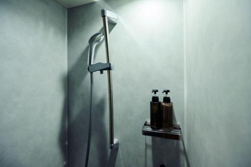 a shower in a bathroom with two bottles on a shelf at The Knot Utsunomiya in Utsunomiya