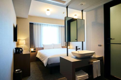 a hotel room with a bed and a sink at The Knot Utsunomiya in Utsunomiya