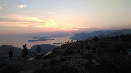 Un gruppo di persone in piedi su una montagna che osservano il tramonto di Room Dragica a Dubrovnik