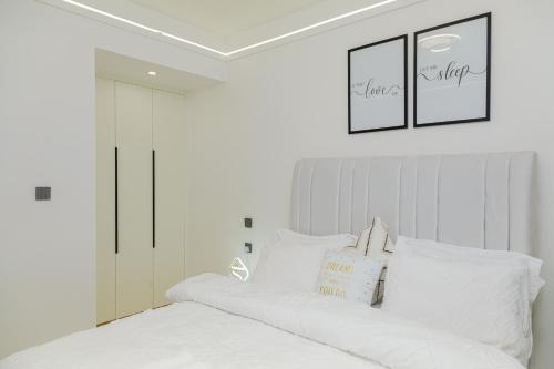 a bedroom with a white bed with two pictures on the wall at Riara One Residency in Gatunga