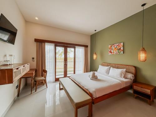 a bedroom with a bed and a desk and a kitchen at Kerti Suite in Munggu