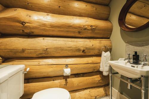 a bathroom with a wooden wall with a toilet and a sink at Keepers Cabin in Ilkley