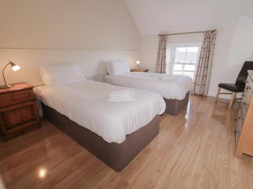 a bedroom with two beds and a desk with a chair at Finn Cottage in Strabane