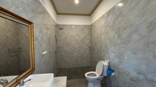a bathroom with a toilet and a sink and a mirror at Shima Tunjung in Darmasaba